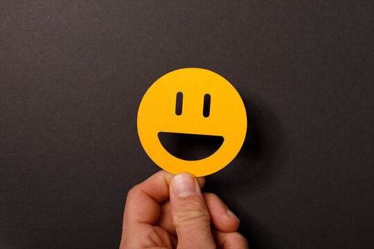 Happy face held in hand expressing positivity, joy, and satisfaction. Ideal for concepts like happiness, menta