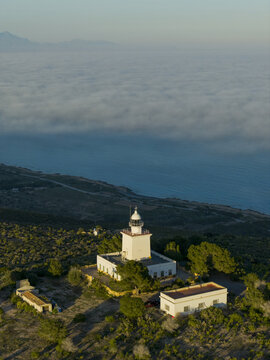 Aerial view of the Faro del Cabo de Santa Pola standing tall amidst the green landscape with the blue sea beyond, Santa Pola, Comunidad Valenciana, Spain.