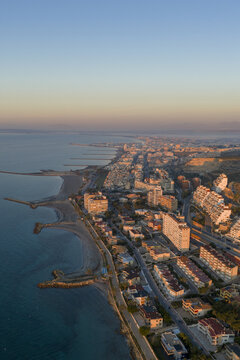Aerial view of the coastline meeting the city, with buildings lining the shore under a gradient sky, Santa Pola, Valencian Community, Spain.