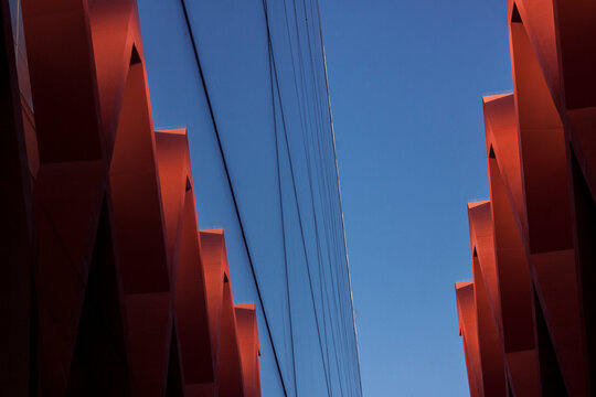 Perspectiva arquitect&oacute;nica abstracta de estructuras geom&eacute;tricas rojas contra cielo azul