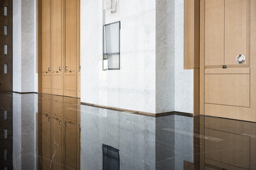 Naklejka premium Modern office corridor with wooden storage cabinets and polished marble flooring reflecting ambient light