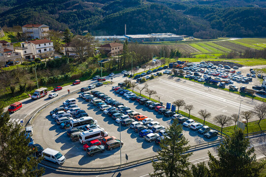 Aerial view of orderly parked cars in a vast lot contrasting with the rolling hills and distant structures, under a clear sky, Buzet, Istria County, Croatia.