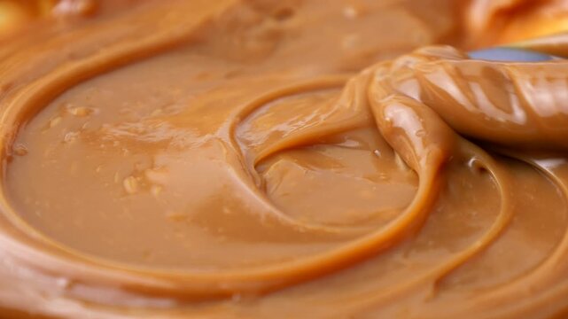 Sweet brown caramel toffee sauce spreading with a spoon close up