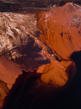 Aerial view of iron-rich earth bleeding into the dark waters, where the red and brown hues contrast starkly with the deep blue, Aluminium Refinery, Western Australia, Australia.