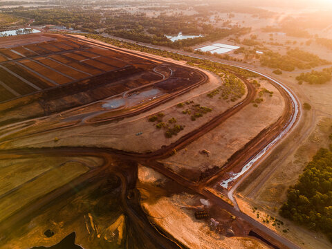 Aerial view of the earth's raw beauty melding with industrial precision, creating a symphony of rust and amber tones under the Australian sun, Aluminium Refinery, Western Australia, Australia.