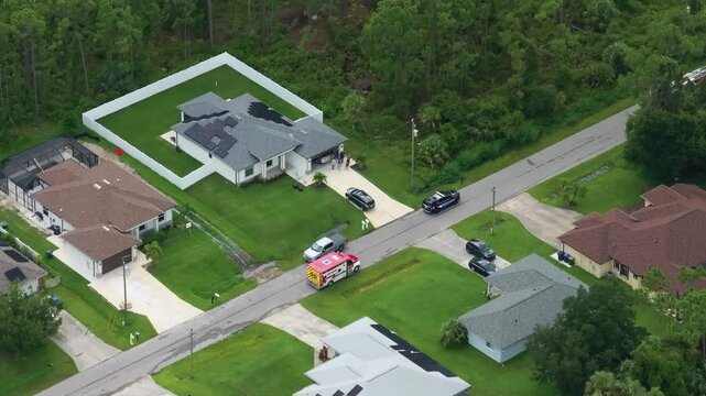 Paramedics assist patient at suburban home as ambulance and fire engine remain stationed outside.