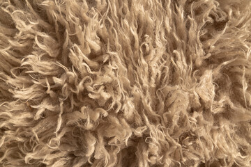 Close-up of beige faux fur texture — soft synthetic wool with curly pile, detailed high-resolution textile background © Vladimir