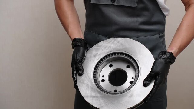 Brake technician prepares disc for replacement and inspection. Workshop technician carefully inspects and prepares ventilated brake disc to ensure safety and replacement. Automotive repair concept