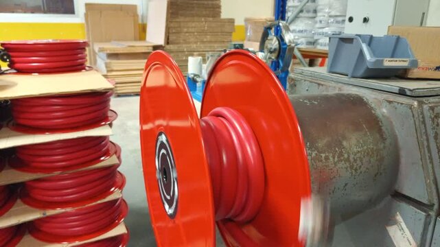 Close up of 1 inch red rubber fire hose winding onto a metal reel for industrial safety"
