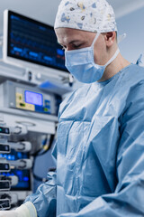 Naklejka premium Surgeon performing operation with medical monitors visible in background. Concept of medical technologies and surgery. 