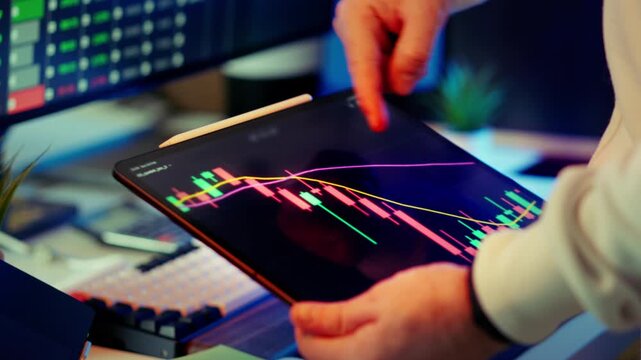 Cryptocurrency market crash analysis tablet trading workspace. Closeup investor hands holding device with red candlestick chart downward trend bearish movement volatility pressure