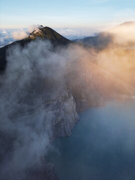 Aerial view of majestic mountains pierce through a sea of swirling clouds, kissed by the warm glow of sunrise, Java, Java, Indonesia.