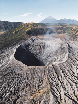 Aerial view of Mount Bromo's rugged crater steams gently under a vast sky, a testament to the earth's raw power, Java, Java, Indonesia.