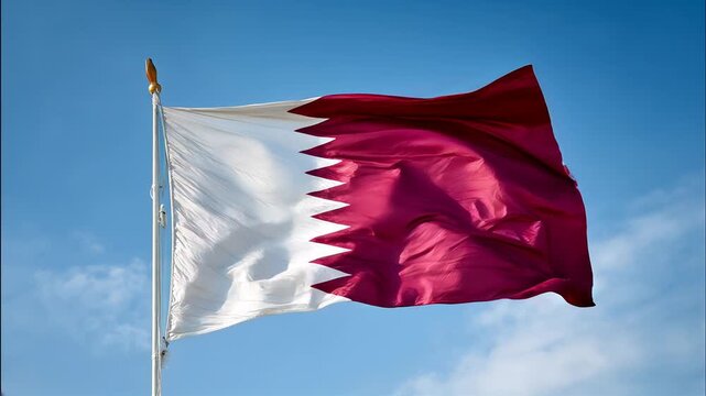 qatari flag waving in the wind. flag of qatar in blue sky