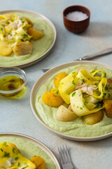 Baked potatoes are topped with slices of fermented zucchini and served alongside a green pea sauce with broccoli. This meal is prepared for a healthy breakfast