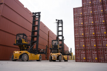 Two yellow forklifts operating in a port container yard with stacked shipping containers © zhu difeng