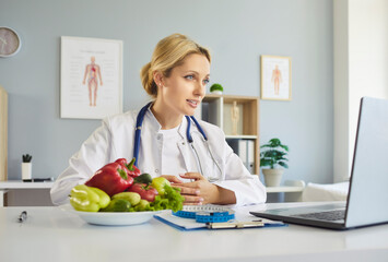 Nutritionist dietitian conducts telehealth consultation via laptop. Fresh vegetables and a measuring tape underscore healthy choices as doctor listens. Concept: expert online nutrition and care.