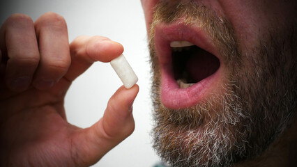 Сlose-up of a man's hand bringing a chewing pad to the mouth to chew it © Stockah