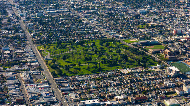 Aerial view of a vast cemetery with verdant green grass and scattered trees amid the urban sprawl, Los Angeles, California, United States.