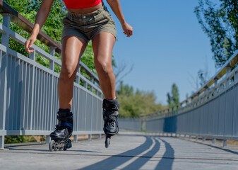 Obraz premium Woman's legs in action rollerblading on elevated walkway under blue sky
