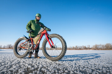 senior male cyclist with his fat mountain bike on a frozen lake in northern Colorado