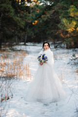 portrait of a young bride in a winter snowy pine forest