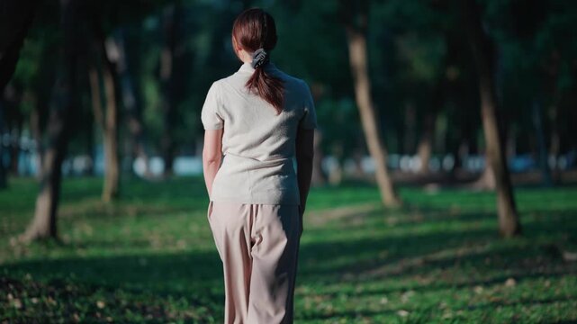 Young asian woman practicing mindfulness meditation while sitting on green grass in forest to improve mental health and find inner peace during a quiet morning in the natural environment