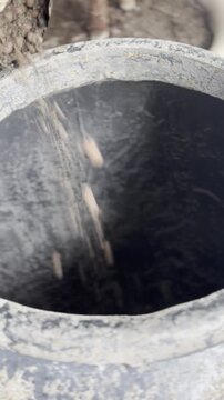 Pouring clay pebbles into plant pot for drainage, houseplant repotting process