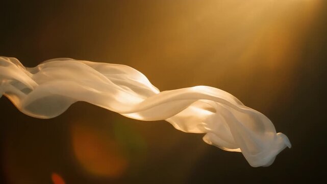 White flowing silk fabric moves gracefully in slow motion against a warm golden sunset background with cinematic sunbeams in this ethereal stock video clip.