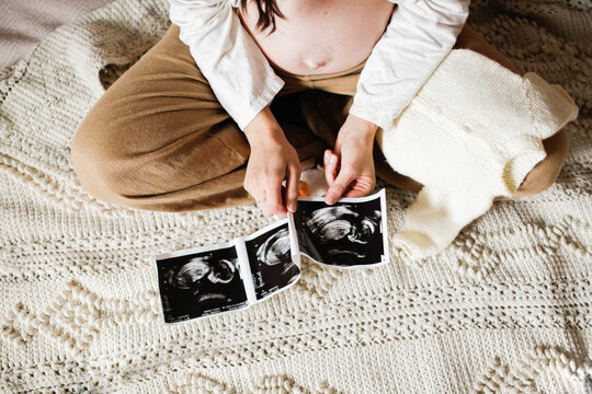 pregnant Mother sitting on bed with baby things