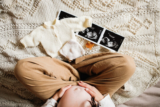 pregnant Mother sitting on bed with baby things