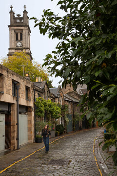 woman with long dark hair on charming cobblestone street in Scotland