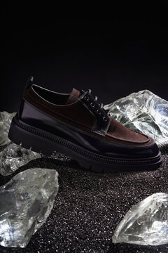 Stylish black and brown shoes on shattered glass surface