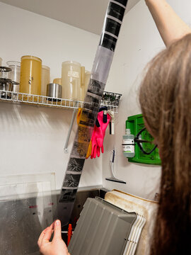 Person Inspecting Developed Film Strips in a Darkroom Setting