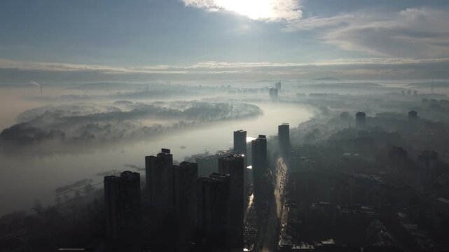 Drone flight above Belgrade city in the smog and fog in the morning. Zemun and New Belgrade district, Serbia, Europe