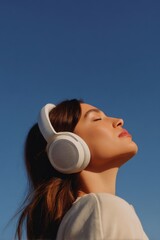A woman wearing white over-ear headphones.