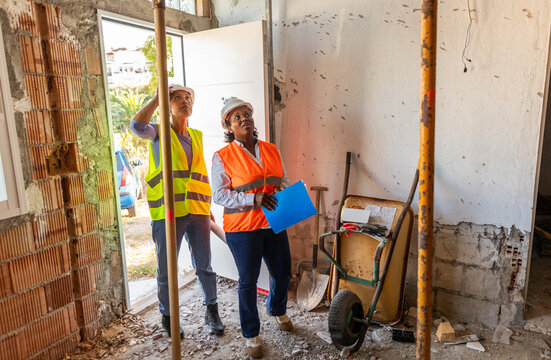 Two female construction managers enter a construction site