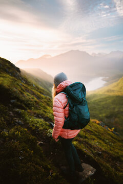Woman travel solo climbing mountains in Norway summer extreme vacations in Lofoten islands, hiking adventure lifestyle traveler outdoor girl mountaineering with backpack freedom endurance morning view