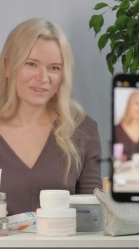 Beauty Influencer Vlogging, Advice with Content Creator, Promotion for Cosmetics Product Live Streaming. Blonde Woman Recording Skincare Tutorial On Smartphone, Jars Of Cream, Serum, Framing Closeup