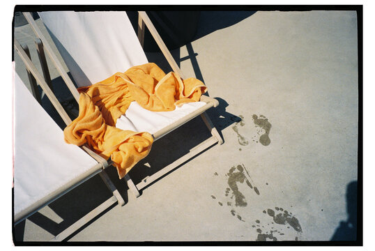 Towel on chair with footprints on concrete poolside area