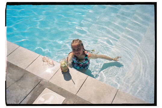 Girl enjoys pool time while holding a drink