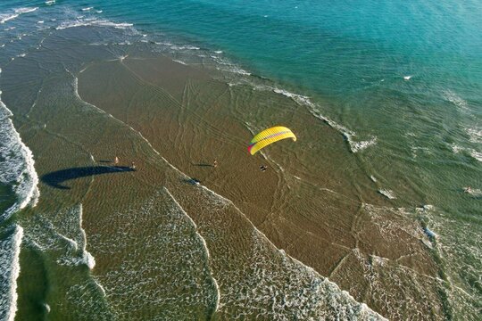 Aerial view of a lone paraglider soaring above the beach, the turquoise ocean contrasting with the sandy shore, Jupiter, Florida, United States.