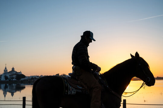 Cowboy On Mustang By Water During Golden Sunset