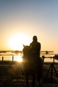 Cowboy On Horse Silhouetted Against Sunrise Sky