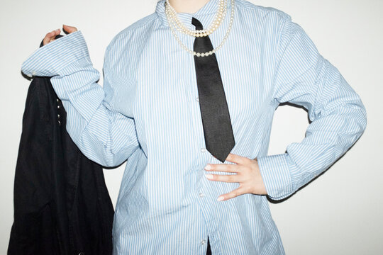 Person wearing suit, tie and shiny pearl necklaces in business office