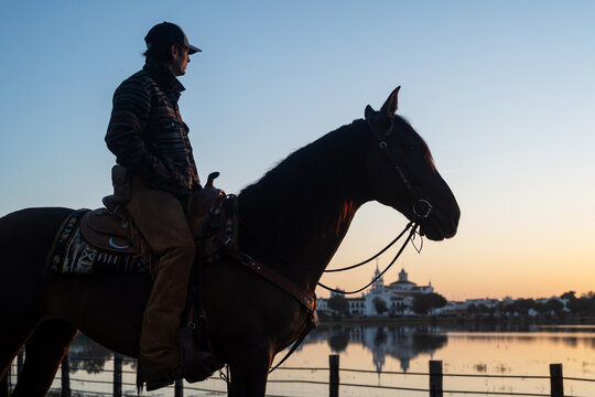 Cowboy On Mustang By Water During Golden Sunset