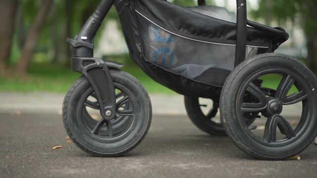 Closeup of stroller wheel on pavement. Detailed view of baby stroller wheel on street surface. Magnified image focusing on stroller wheel showcasing durability and grip in city conditions