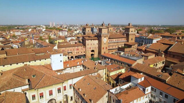 Ferrara aerial 4k drone flight over red roofs to Castello Estense castle. Emilia Romagna Italy medieval city skyline and Estense fortress. Scenic urban landscape and red tiles scenery