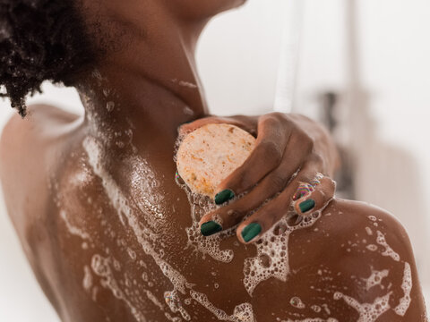 Woman taking shower and applying soap 