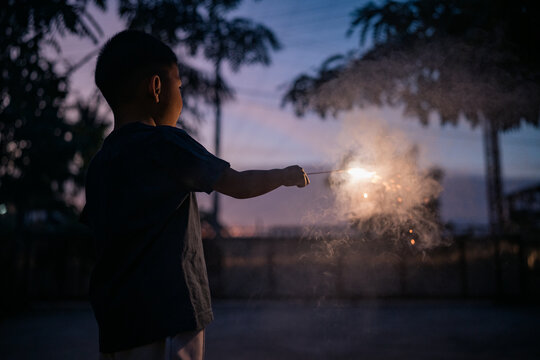 An Asian boy excitedly holds lit sparklers